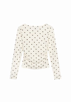 Top de manga larga en tejido crema con un lado fruncido, decorado con un patrón de pequeños lunares marrones en toda la prenda. Textura suave y ligera.