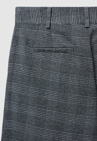 Pantaloni grigi a quadri caratterizzati da un tessuto testurizzato, un sottile motivo a scacchi, passanti per cintura e una singola tasca posteriore senza hardware visibile.
