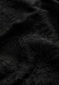 Tissu en dentelle noire avec un motif floral, présentant des détails complexes et des textures variées, apparence douce et drapée.