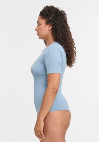 Svetlomodrý priliehavý body s krátkym rukávom, hladká štruktúra, okrúhly výstrih, bočný pohľad, ktorý zvýrazňuje kontúry tela a dizajn rukávov.