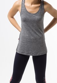 Grijze sport tanktop met een ronde hals en racerback ontwerp, gecombineerd met marineblauwe leggings met rode zijkanten.