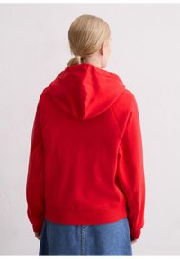 Rode hoodie met een ruime capuchon en geribbelde boord. Gemaakt van zachte stof, met een comfortabele pasvorm en een naadloos schouderontwerp.