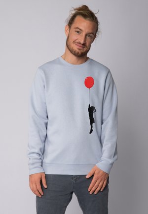 Himmelblauer Baumwoll-Sweatshirt mit einer schwarzen Silhouette, die einen roten Ballon hält, mit gerippten Bündchen und Saum sowie einem Rundhalsausschnitt.
