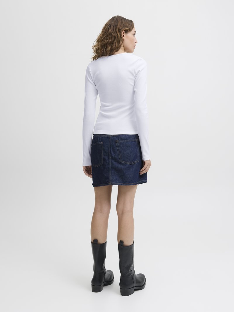 Hvit langermet ribbet topp, denimskjørt med lommer, og svarte lærknestøvler med kraftige hæler. Enkelt og tettsittende design.