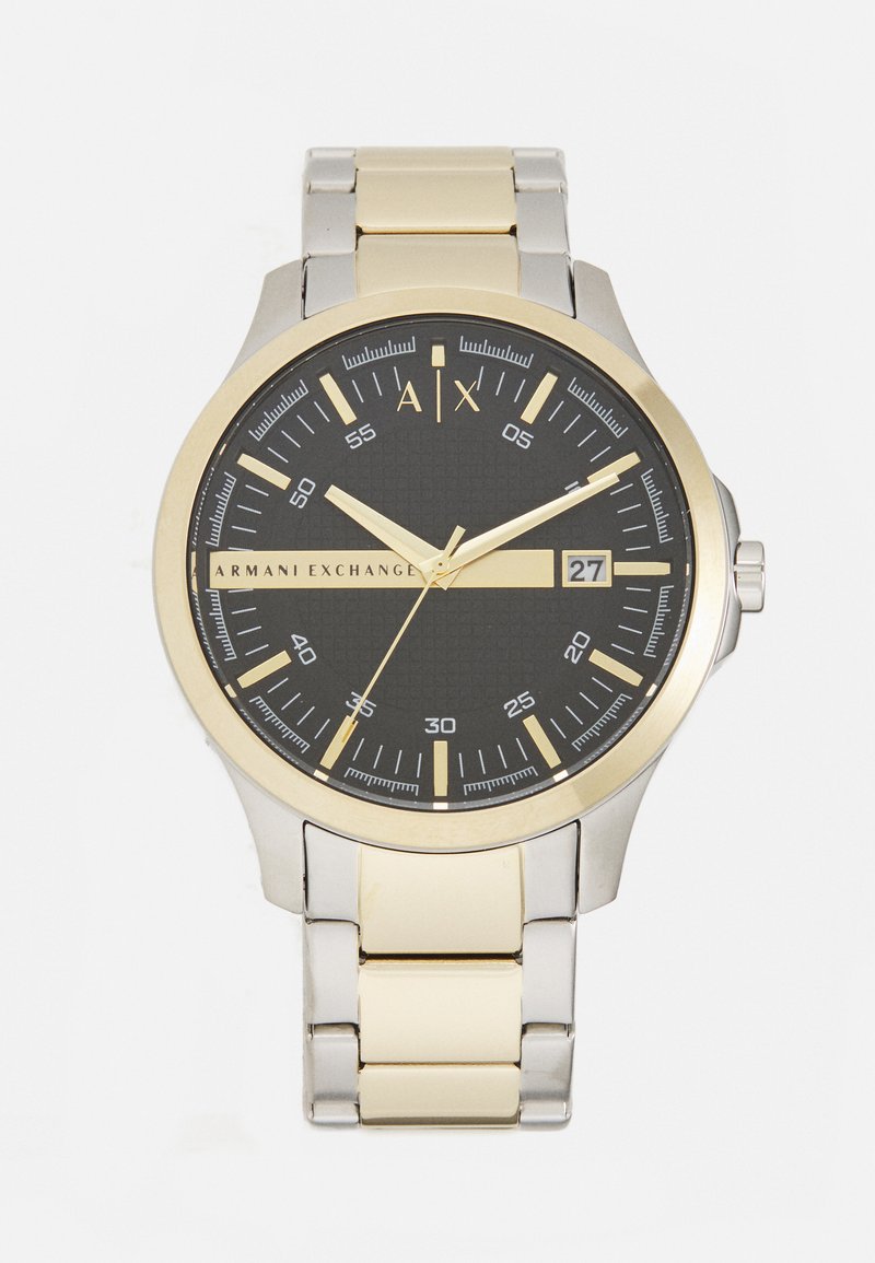 Armani Exchange pulkstenis ar melnu teksturētu ciparnīcu, zelta akcentiem, sudraba un zelta nerūsējošā tērauda siksnu un datuma displeju pie 3 stundām.