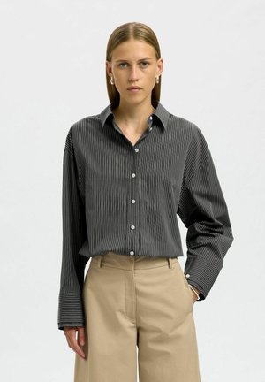 Camicia abbottonata grigia scura con righe verticali, dotata di colletto, maniche lunghe e vestibilità rilassata. Bottoni chiari adornano la parte frontale.
