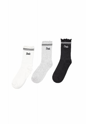 Trois chaussettes côtelées blanches, grises et noires avec des hauts à volants et "Dash" brodé près du bord-côte, chacune avec deux bandes horizontales au-dessus.