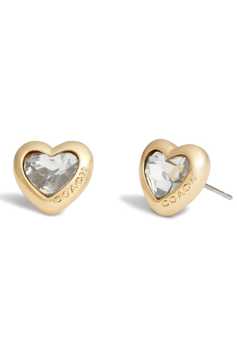 Boucles d'oreilles en forme de cœur en ton or avec un centre en pierre facettée transparente ; présente l'inscription "COACH" gravée sur un côté. Finition lisse, surface polie.