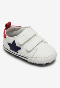 Sneaker bianco per bambino con due cinturini in velcro, accentato da una stella blu e un tab sul tallone rosso. Suola in gomma testurizzata con motivo blu e bianco.