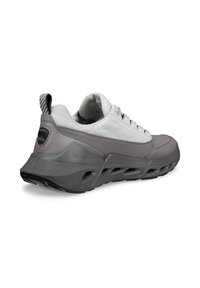 Γκρι και λευκό αθλητικό παπούτσι με γλωττίδα από δίχτυ, λαστιχένια σόλα, σχέδιο με κορδόνια και υφασμένο πίσω διακοσμητικό στοιχείο. Διαθέτει λογότυπο της μάρκας στο πλάι.