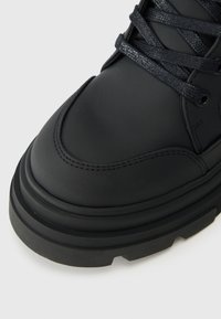 Sneakeruri înalte din piele neagră, cu șireturi texturate negre, guler căptușit și o talpă groasă din cauciuc cu un profil modelat.