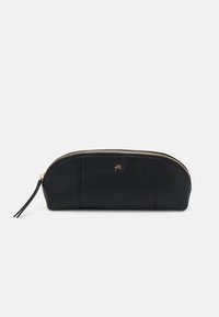 Pochette cosmétique en cuir noir avec une forme arrondie, fermeture éclair dorée et un petit logo. Texture lisse et design minimaliste.