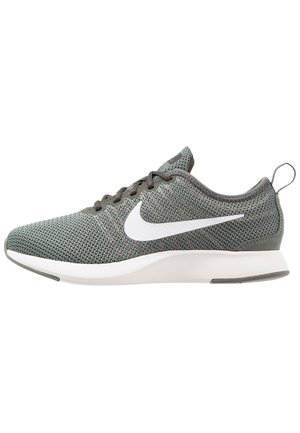 Grijze gebreide Nike hardloopschoen met wit swoosh-logo, witte zool en trektab aan de hiel, zijaanzicht.