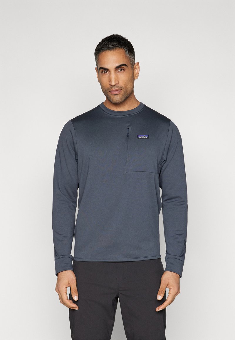 Langermige, marineblauwe shirt van glad synthetisch materiaal, met een klein ritszakje op de borst en een geribbelde kraag.