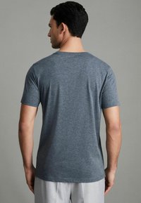 Tricou gri cu mânecă scurtă, confecționat dintr-un material moale, cu un decolteu clasic și o croială lejeră, văzut din spate.