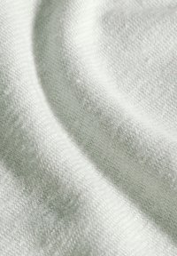 Ljust grått stickat tyg med en fin textur, som visar mjuka, släta fibrer och subtila variationer i mönster över ytan.