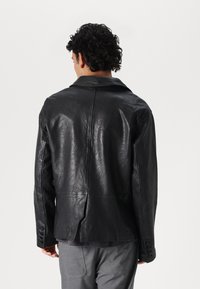 Schwarze Lederjacke mit glatter Textur, großem Kragen und Dreiknopfmanschetten. Verfügt über einen Mittelrinne im Rückenbereich für mehr Bewegungsfreiheit.