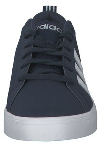 Zapatilla de color azul marino con rayas blancas, puntera redonda, parte superior texturizada y cordones; suela plana de goma blanca; logotipo de la marca en la lengüeta y en la etiqueta del talón.