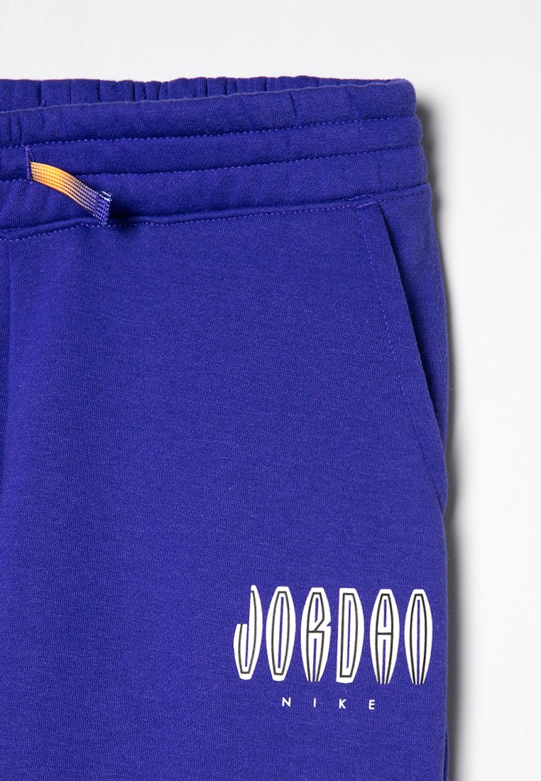 Blaues Sweatshirt-Gewebe mit elastischem Bund, das ein weiß gedrucktes "JORDAN"-Logo und den Text "NIKE" zeigt, mit einem kleinen orangefarbenen Akzent am Bund.