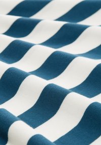 Prugasta tkanina sizmjenjući valovite uzorke u tirkiznoj i bijeloj boji. Tekstura izgleda meko s glatkom završnom obradom i uniformnim dizajnom.