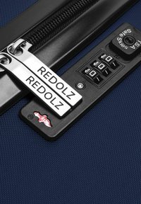 Navy koffer close-up met dubbele metalen ritsen gemarkeerd "REDOLZ", een combinatie-slot met een zwarte paneel, en een gladde textuur.