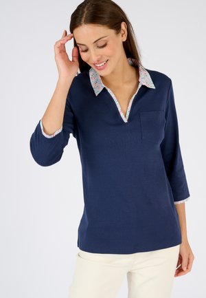 Marineblaues Langarmshirt mit floral gemustertem Kragen und Manschetten. Es verfügt über einen V-Ausschnitt, eine Brusttasche und eine glatte Textur.