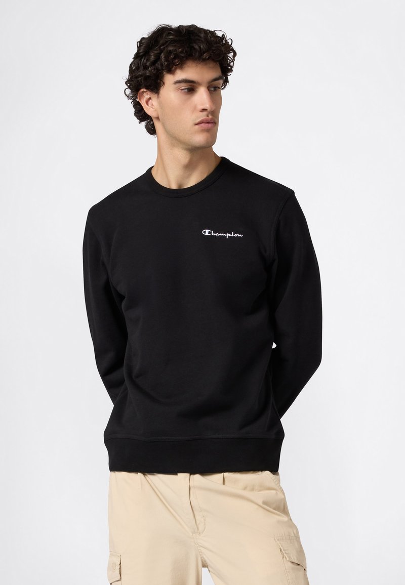 Schwarzer Sweatshirt aus Baumwolle mit Rundhalsausschnitt, langen Ärmeln und kleinem weißem "Champion"-Logo auf der Brust.