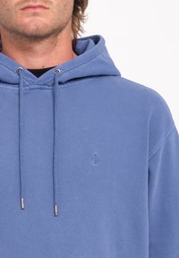Felpa con cappuccio blu chiaro, dotata di cordini, presenta un piccolo logo ricamato sul petto e un tessuto testurizzato.