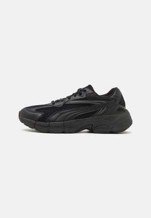 Czarny sportowy sneaker z siateczką i syntetycznymi nakładkami, zawiązywany na sznurówki, z wyściełanym kołnierzem i grubą, teksturowaną podeszwą, pokazany z profilu.