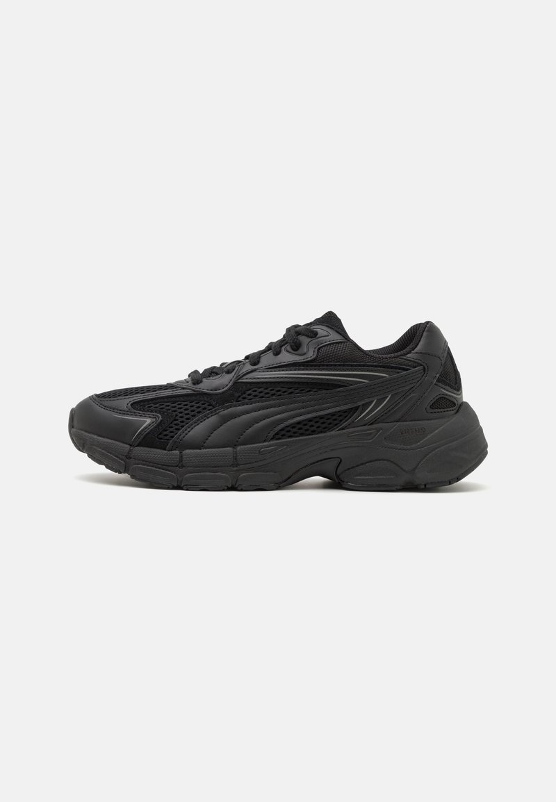 Baskets de sport noires avec mesh et empiècements synthétiques, fermeture à lacets, col rembourré et semelle épaisse texturée, vues de profil.