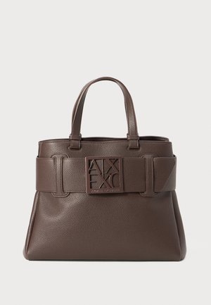 Brown leather handbag with pebbled texture, top handles, and a prominent logo on a belt-like strap. Features angular accents and a structured shape.