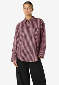 Stripet skjorte i burgunder og rosa med vanlig krage, lange ermer og en brystlomme med logodetalj. Maskinvaskbart stoff.