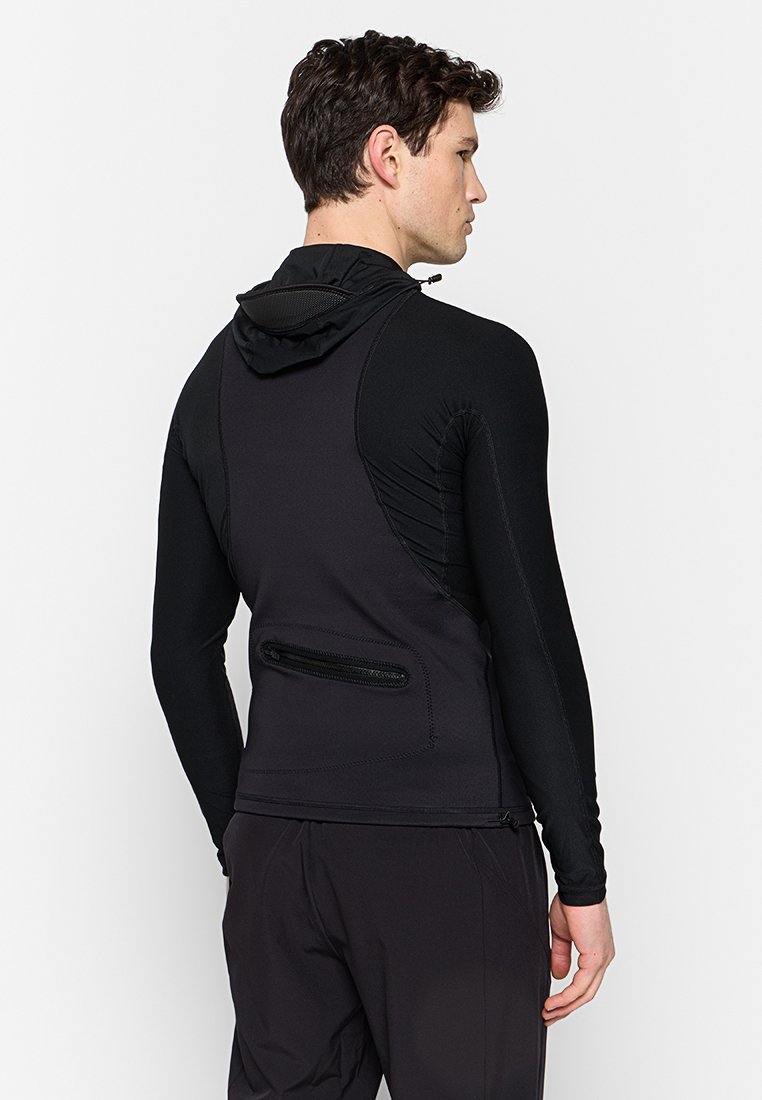 Czarna sportowa kurtka z kapturem, z fakturowanym panelem i zasuwaną kieszenią na plecach. Dopasowany krój z długimi rękawami i elastycznym materiałem.
