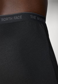 Boxer da uomo neri con una cintura morbida ed elastica con la scritta "THE NORTH FACE" stampata in grigio scuro. Texture del tessuto liscia e elastica.