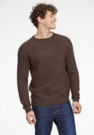 Brun cable-knit sweater med ribbede mansjetter og kant, lavet af struktureret garn, parret med mørkeblå jeans. Enkel rund halsudskæring.