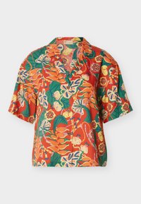 Κοντομάνικο πουκάμισο με κουμπιά, με ζωντανά τροπικά λουλουδάτα και φυλλώδη σχέδια σε πορτοκαλί, πράσινο, κίτρινο και μπλε πάνω σε κόκκινο φόντο.