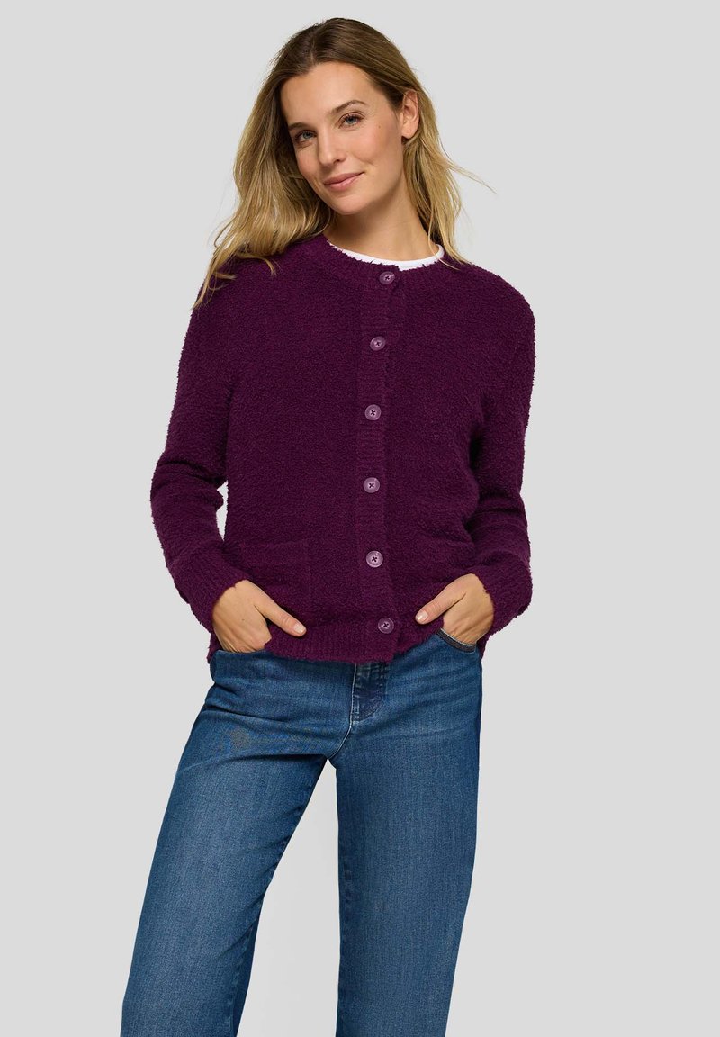 Purple textured cardigan with a round neck, featuring six buttons, front pockets, and long sleeves, paired with blue jeans.