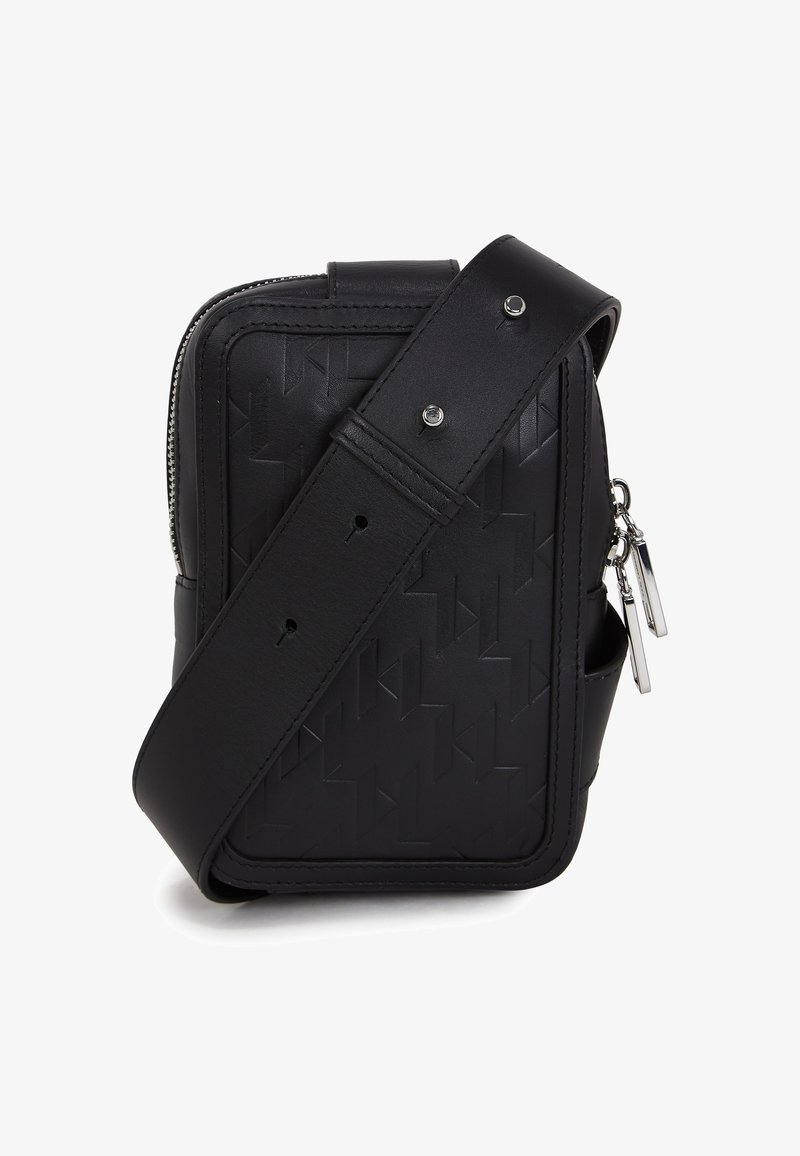 Melnas ādas plecu soma ar ģeometrisku reljefu, sudraba rāvējslēdzis un regulējamu siksniņu. Izceļas ar gludu taisnstūra dizainu.