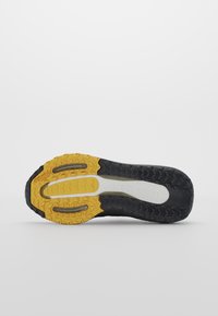Semelle de chaussure avec une bande de roulement noire et jaune avec du caoutchouc Continental pour une meilleure traction, vue de dessous sur un fond uni.