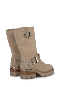 Bottines en daim tan avec une sangle à boucle, ornées de clous et de gemmes au niveau du talon, et une semelle épaisse et texturée.