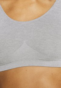 Bralette gris sin costuras con banda acanalada, tela de mezcla de algodón suave, diseño de escote amplio y sutil detalle de costura triangular.