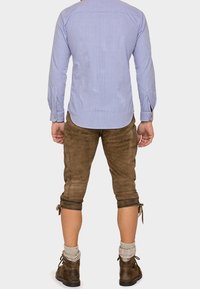 Chemise à manches longues à carreaux bleu et blanc, lederhosen en cuir marron, manches retroussées, chaussettes grises et chaussures marron. Détails de tissu texturé visibles.