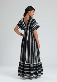 Maxi dress con scollo a V, schiena scoperta, maniche corte. Tessuto nero con righe bianche e motivi intricati; gonna fluida con orlo arricciato.