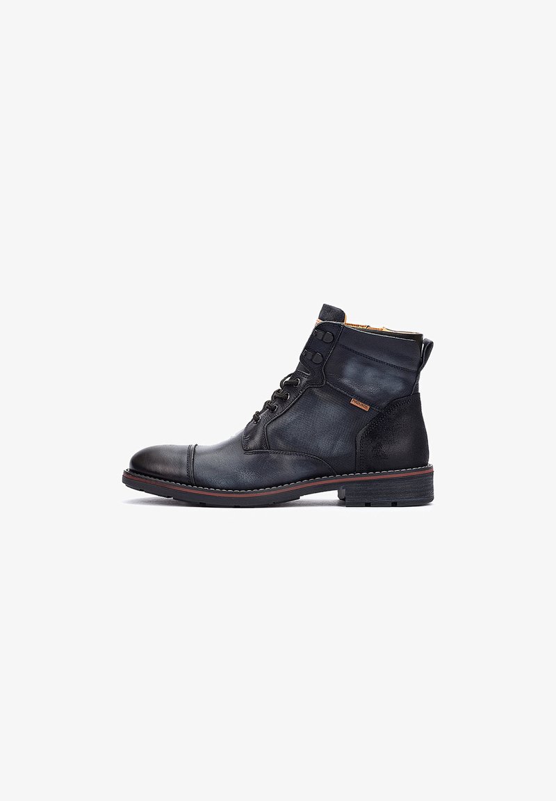Botín de cuero negro hasta el tobillo con un acabado suave, puntera redonda, costuras en contraste y diseño de cordones. Cuenta con acentos de tela texturizada.