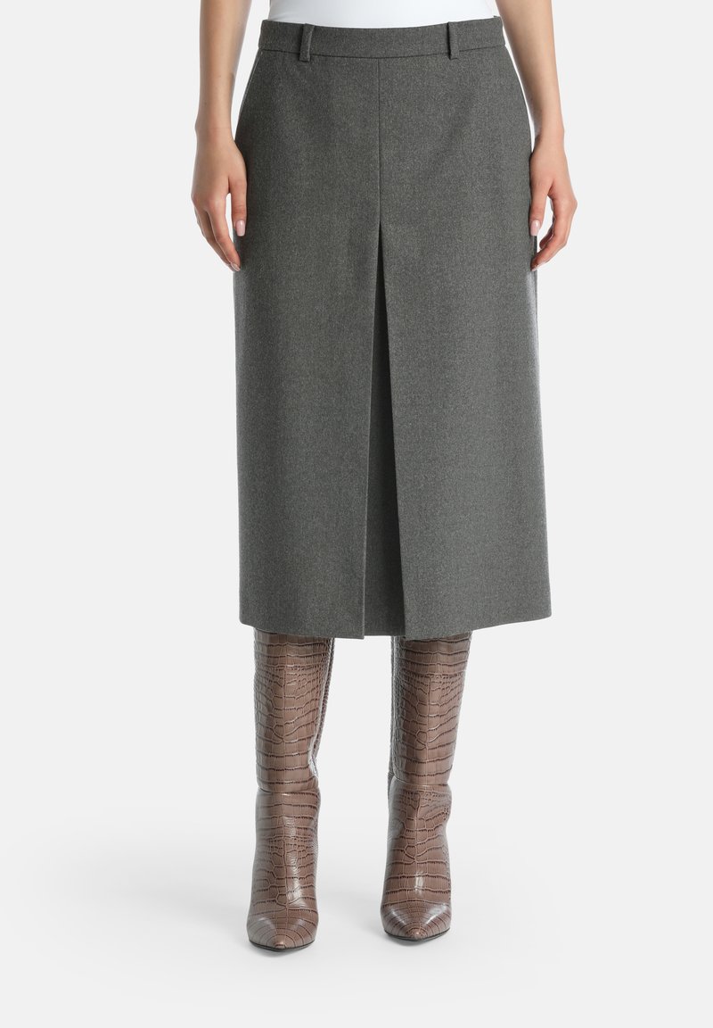 Grå ull knälång kjol med design av framfåll, tillsammans med knähöga, texturerade bruna stövlar i krokodilprägling.