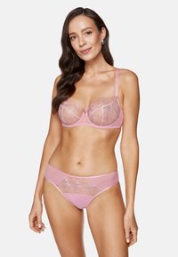Jasnoróżowy zestaw bielizny składający się z przezroczystego koronkowego biustonosza z kwiatowymi wzorami oraz pasujących majteczek, obie części wykonane z gładkiego materiału i ozdobione delikatnymi detalami.