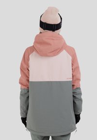 Färgglad vattentät skidjacka i ljusrosa, mjukrosa och grå. Har huva, justerbara detaljer och en avslappnad passform.