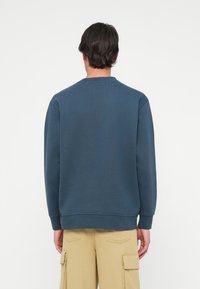 Marineblauwe sweatshirt met een ronde hals, geribbelde mouwen en onderrand. Gemaakt van zachte stof, met een gladde textuur zonder zichtbare graphics.