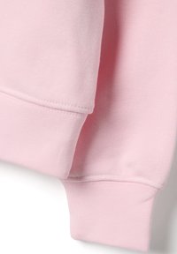 Manche de sweat-shirt en coton rose clair présentant un poignet côtelé et un détail de couture. Texture douce et finition lisse.