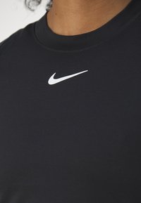 Camiseta deportiva negra hecha de material elástico, con cuello redondo y un pequeño logo de Nike en blanco en el pecho.